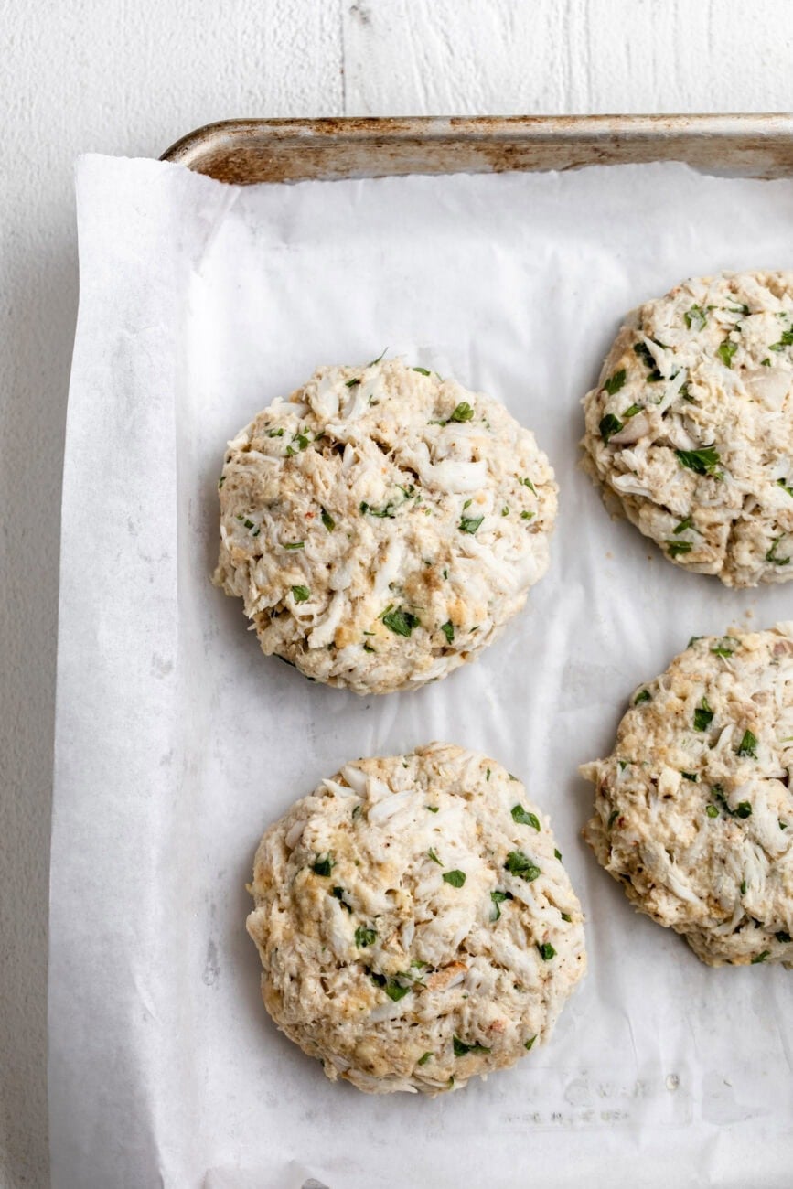 shaped maryland style crab cakes on parchment paper lined baking sheet.