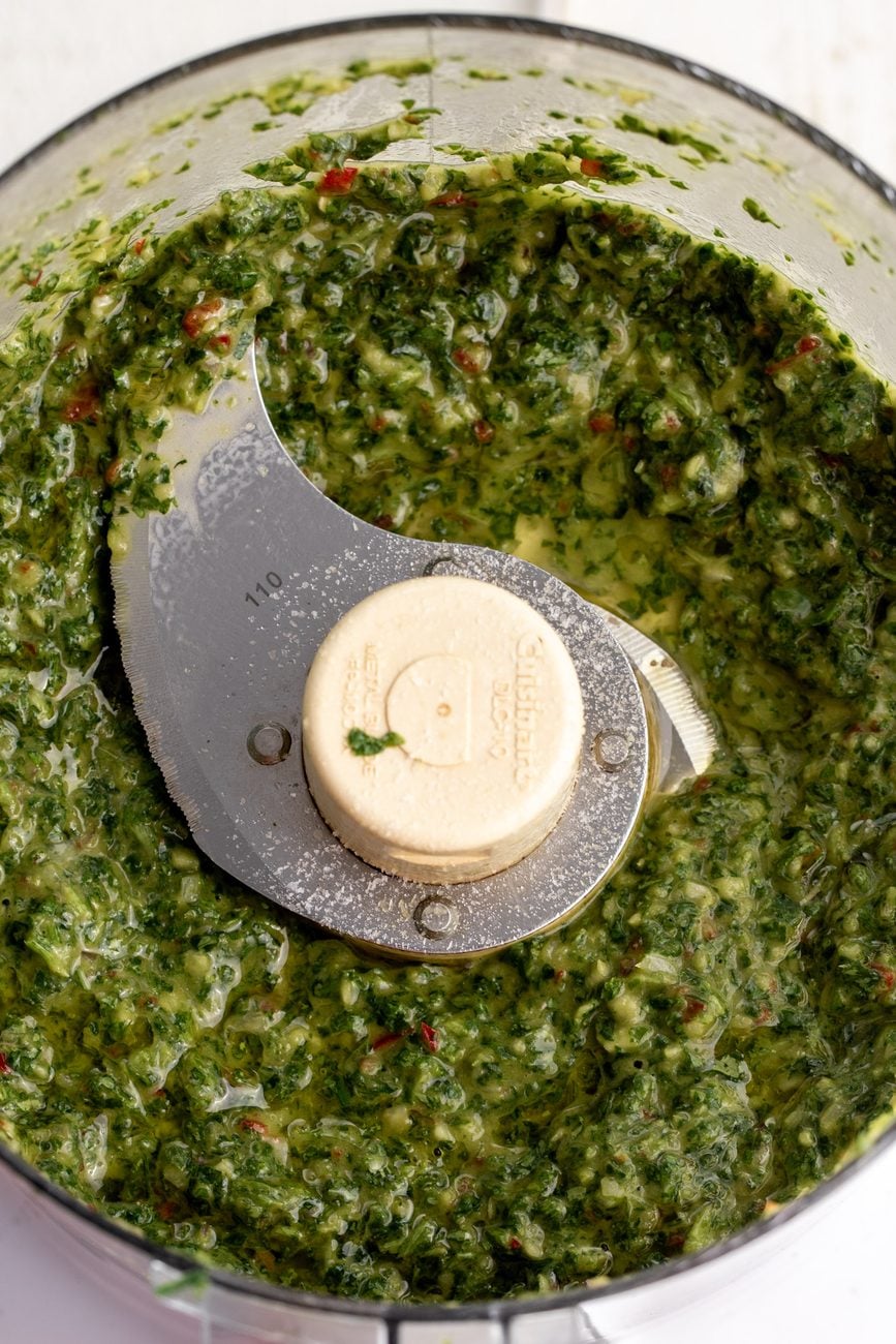 blended chimichurri in food processor made with fresh herbs.