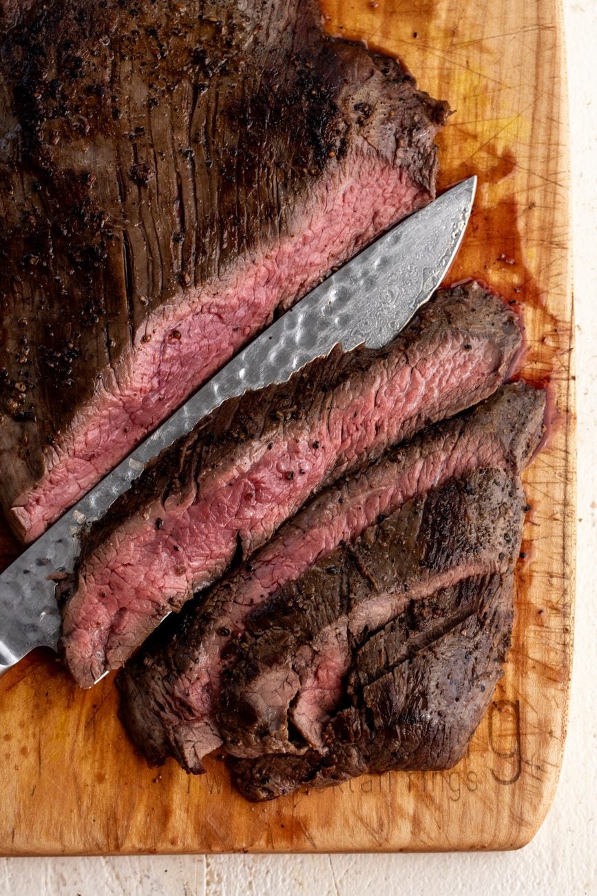 rested flank steak sliced on cutting board. 