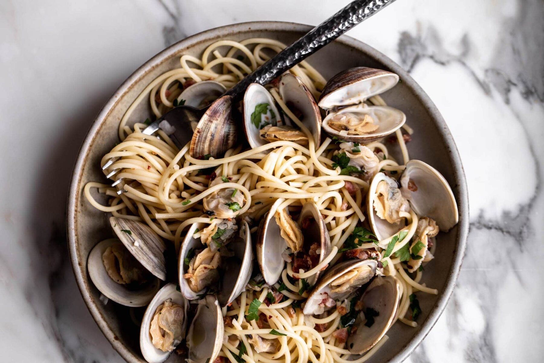 spaghetti alle vongole with clams in bowl with fork and littleneck clams.