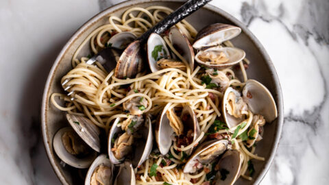 spaghetti alle vongole with clams in bowl with fork and littleneck clams
