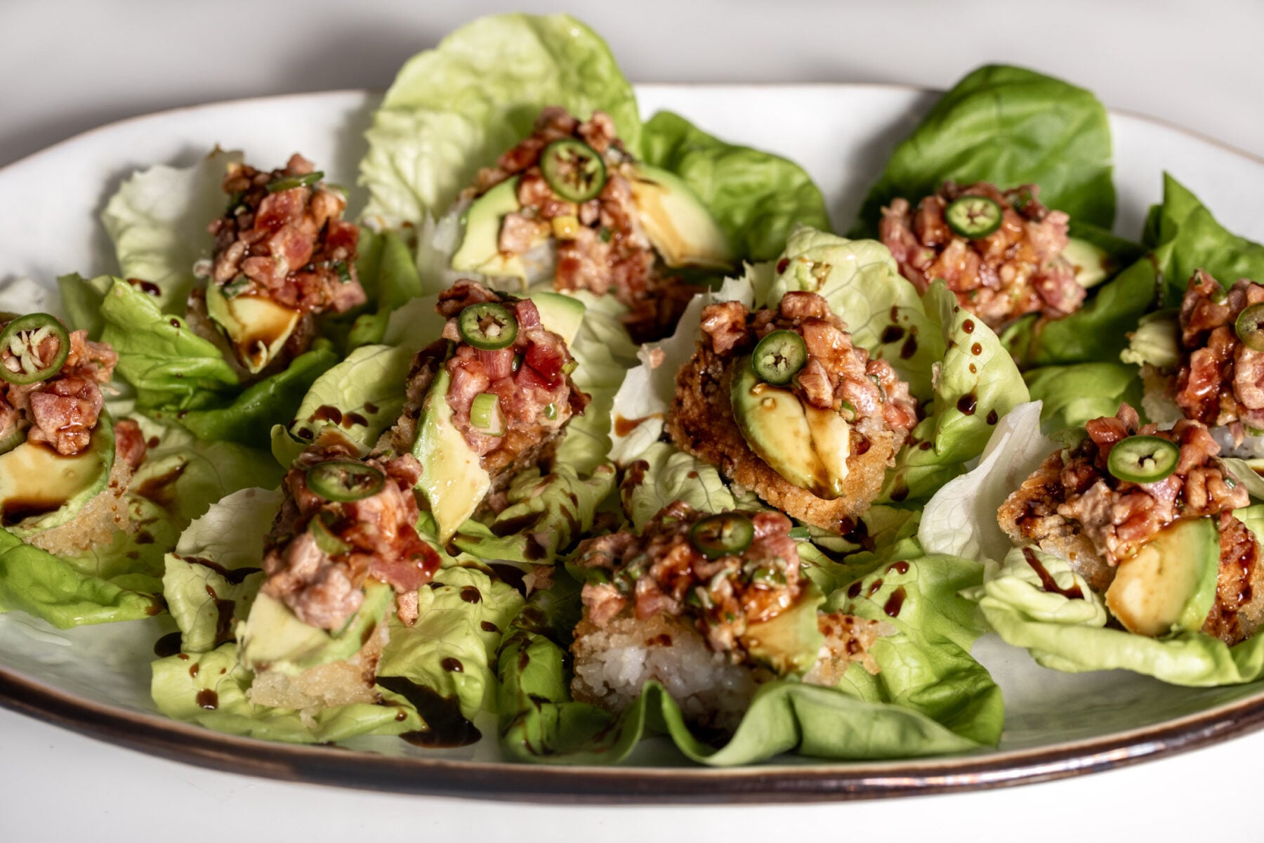 Crispy Rice Topped with Spicy Tuna avocado and jalapeño drizzled with eel sauce in butter lettuce cups.