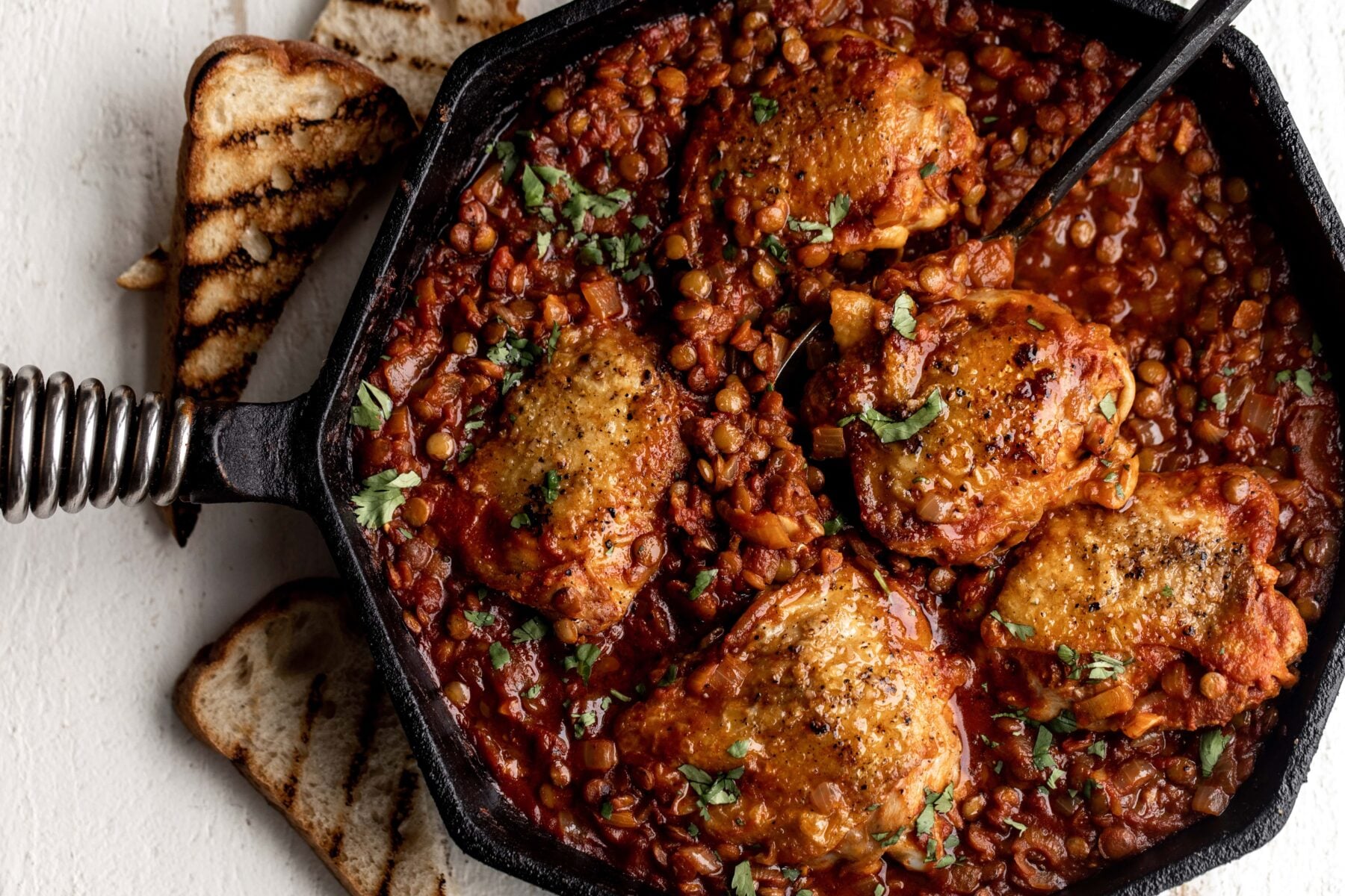 One-Pan seared Chicken Thighs with Harissa Lentils and tomatoes.