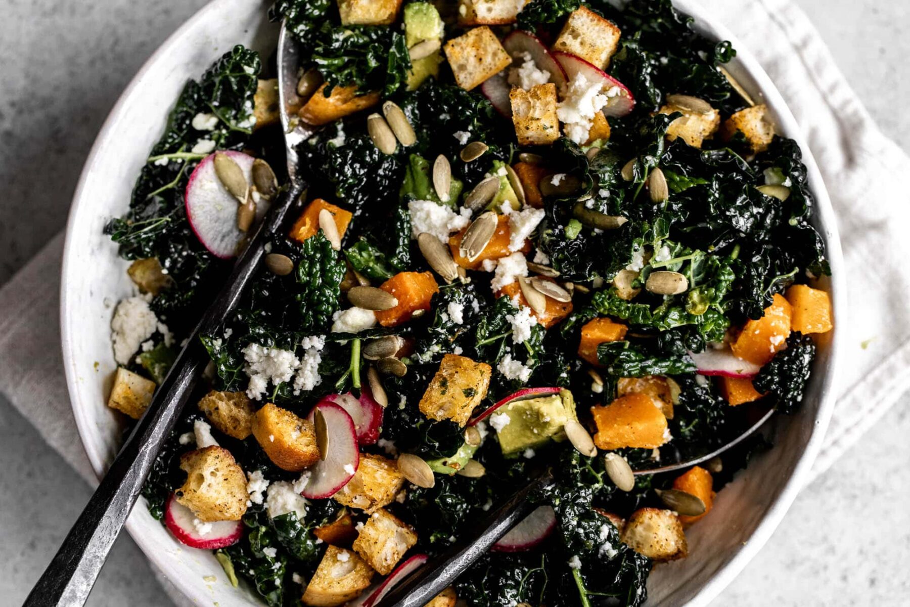 mexican-inspired kale salad with roasted butternut squash, cilantro croutons lime dressing pepitas and queso fresco.