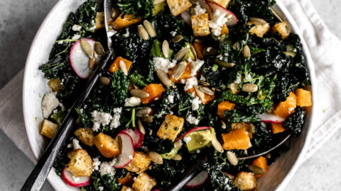 mexican-inspired kale salad with roasted butternut squash, cilantro croutons lime dressing pepitas and queso fresco