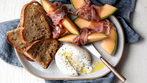 burrata and prosciutto snack plate with cantaloupe and toasted garlic bread
