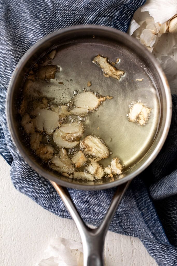 garlic oil in small saucepan on blue towel.