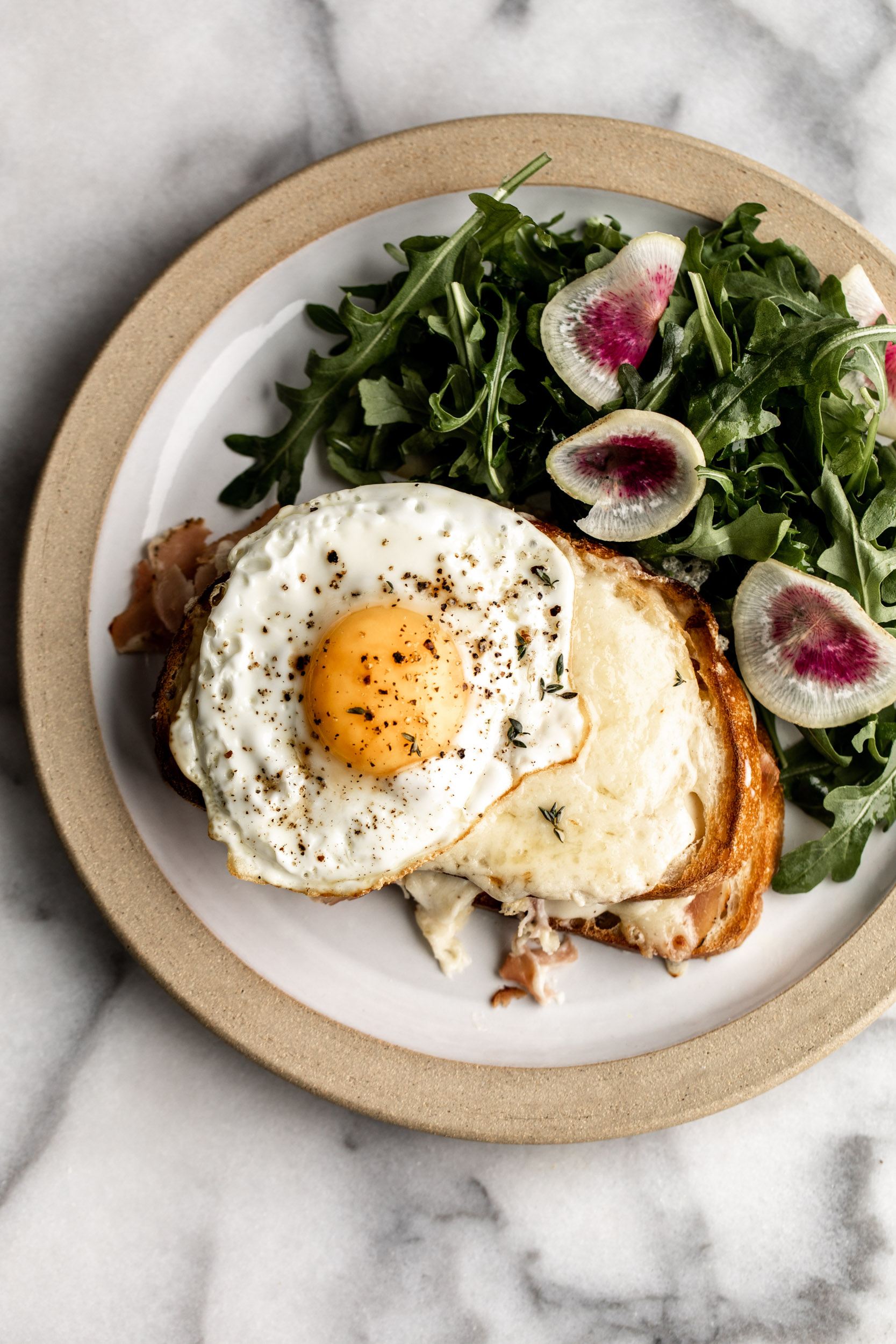 Croque Madame topped with mornay sauce and melted gruyere cheese topped with fried egg