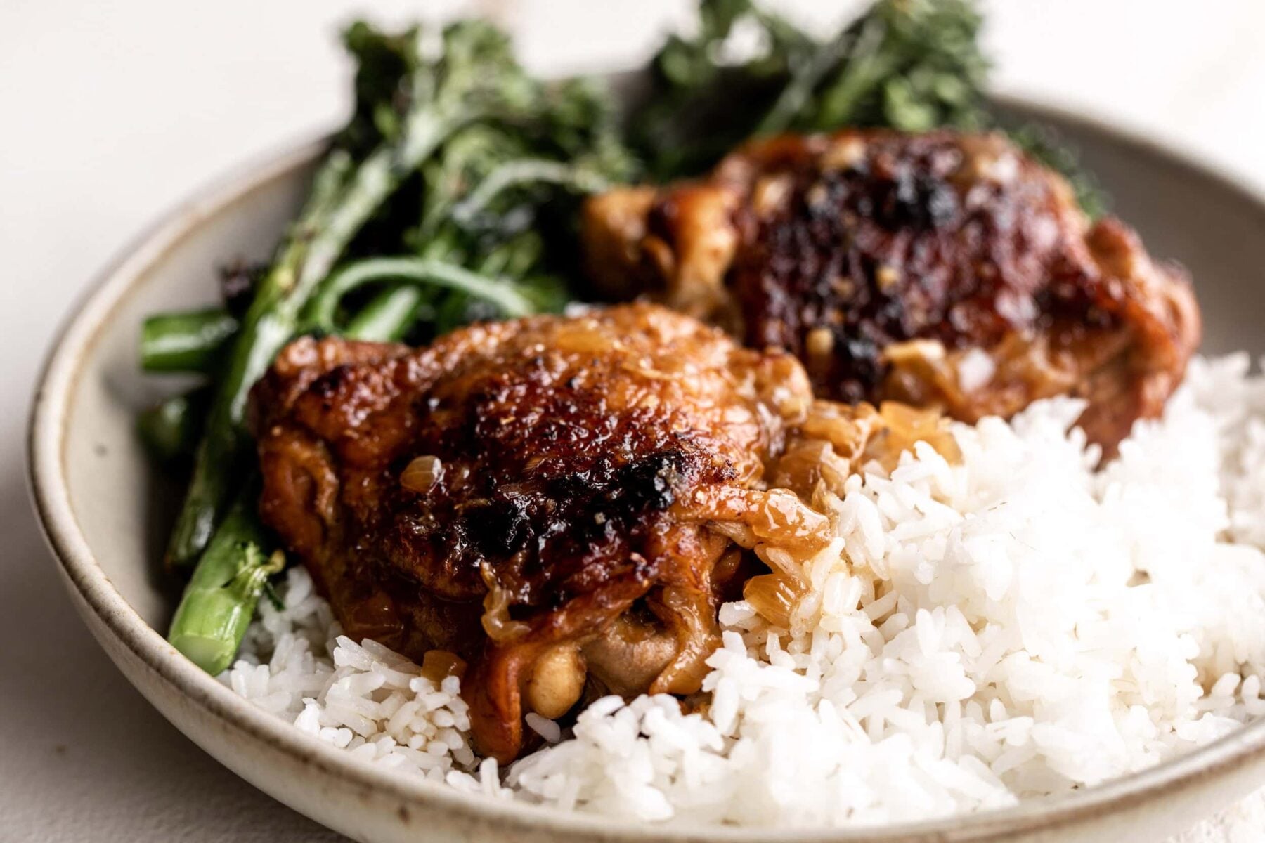 lemongrass braised chicken thighs on a bed of rice with a side of roasted broccolini.