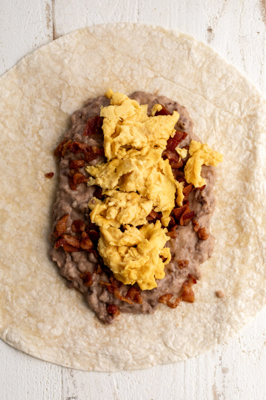 layered refried pinto beans, crumbled cooked bacon and scrambled eggs on tortillas.