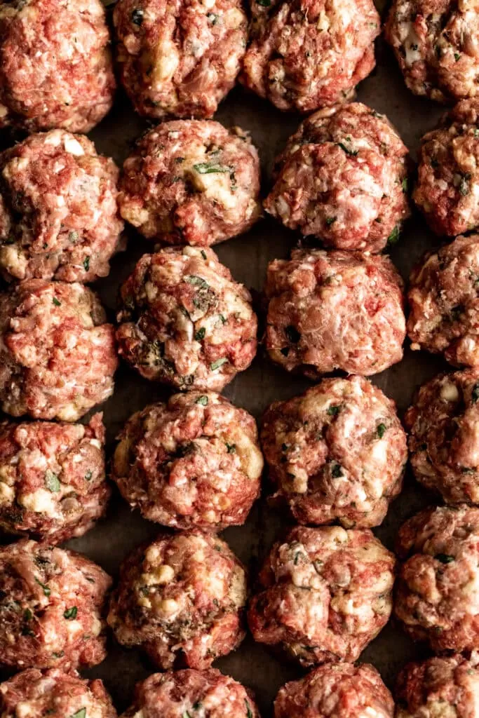 beef pork and prosciutto bmeatballs on baking sheet in rows