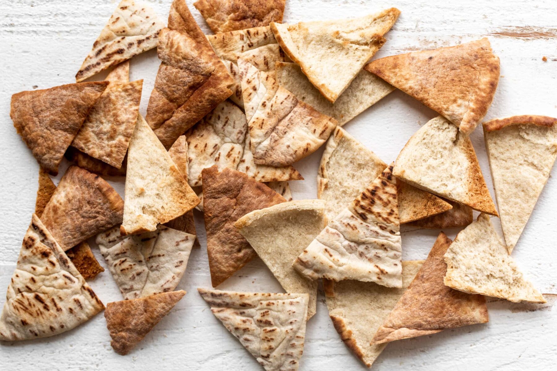 baked pita chips on white wood.