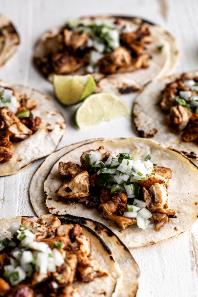 Mexican chicken street tacos on corn tortillas with onion salsa and limes