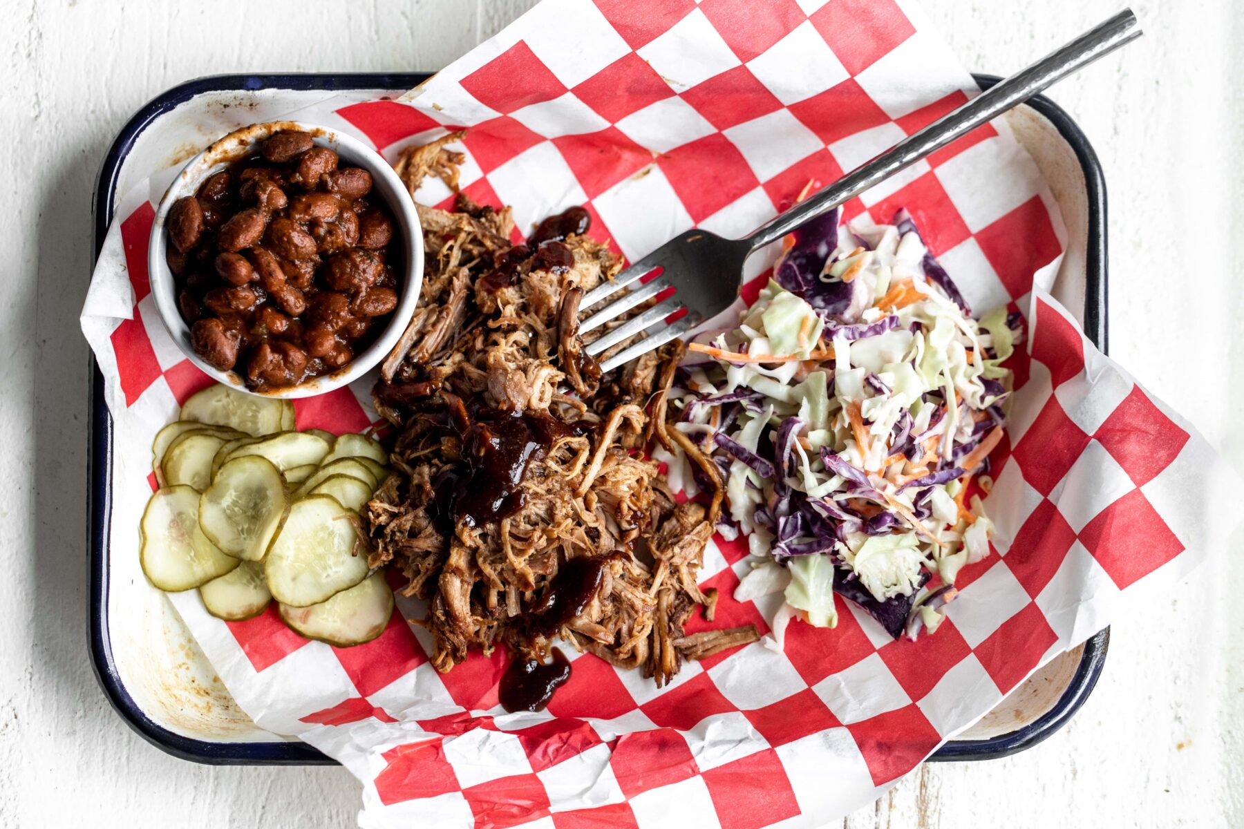How to make pulled pork in the oven served on platter with coleslaw and bbq beans.
