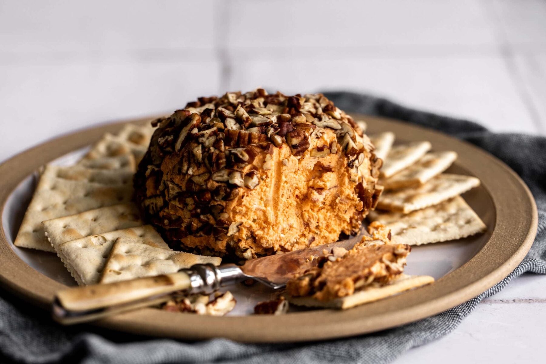 Pimento cheese ball on board with crackers.
