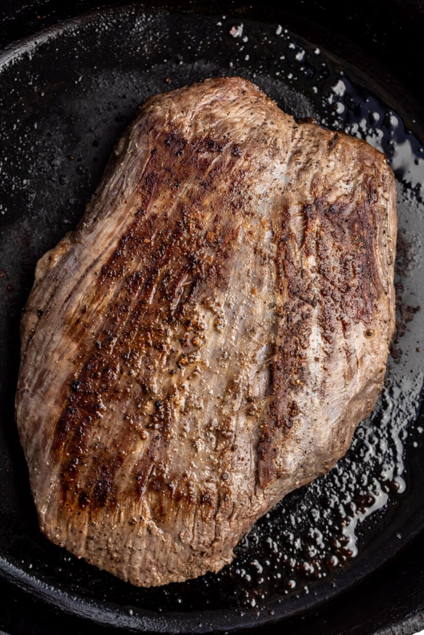 pan-seared flank steak in cast iron pan.