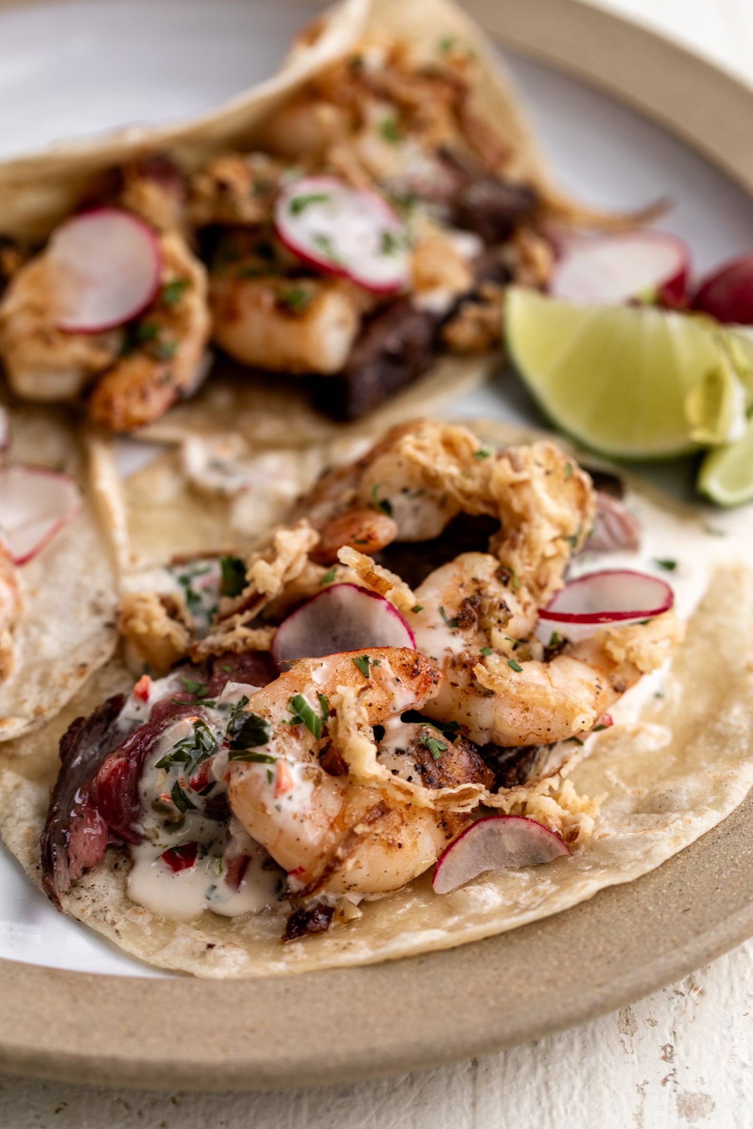 Surf and turf tacos with crispy onions and chimichurri aioli.