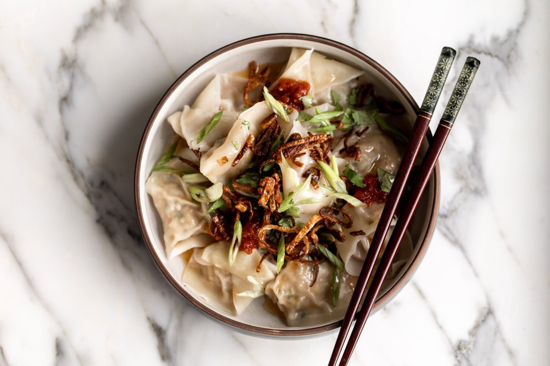 spicy sichuan wontons filled with pork and shrimp with chili oil, chili sauce and crispy shallots.