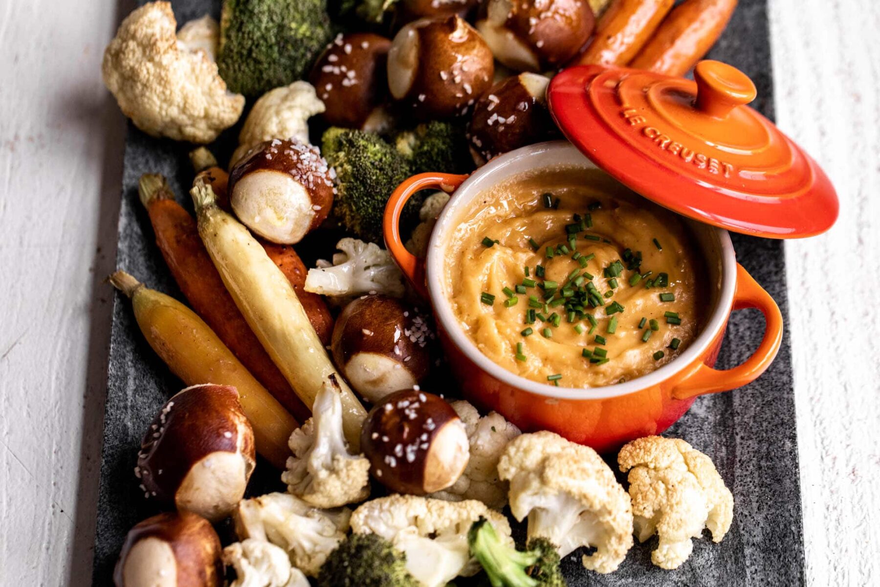 cheddar beer cheese fondue with roasted vegetables and pretzel balls.