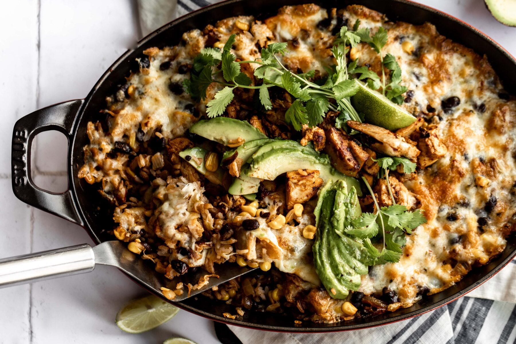 One pan cheesy rice and bean bake with chipotle adobo chicken topped with avocado and cilantro. 