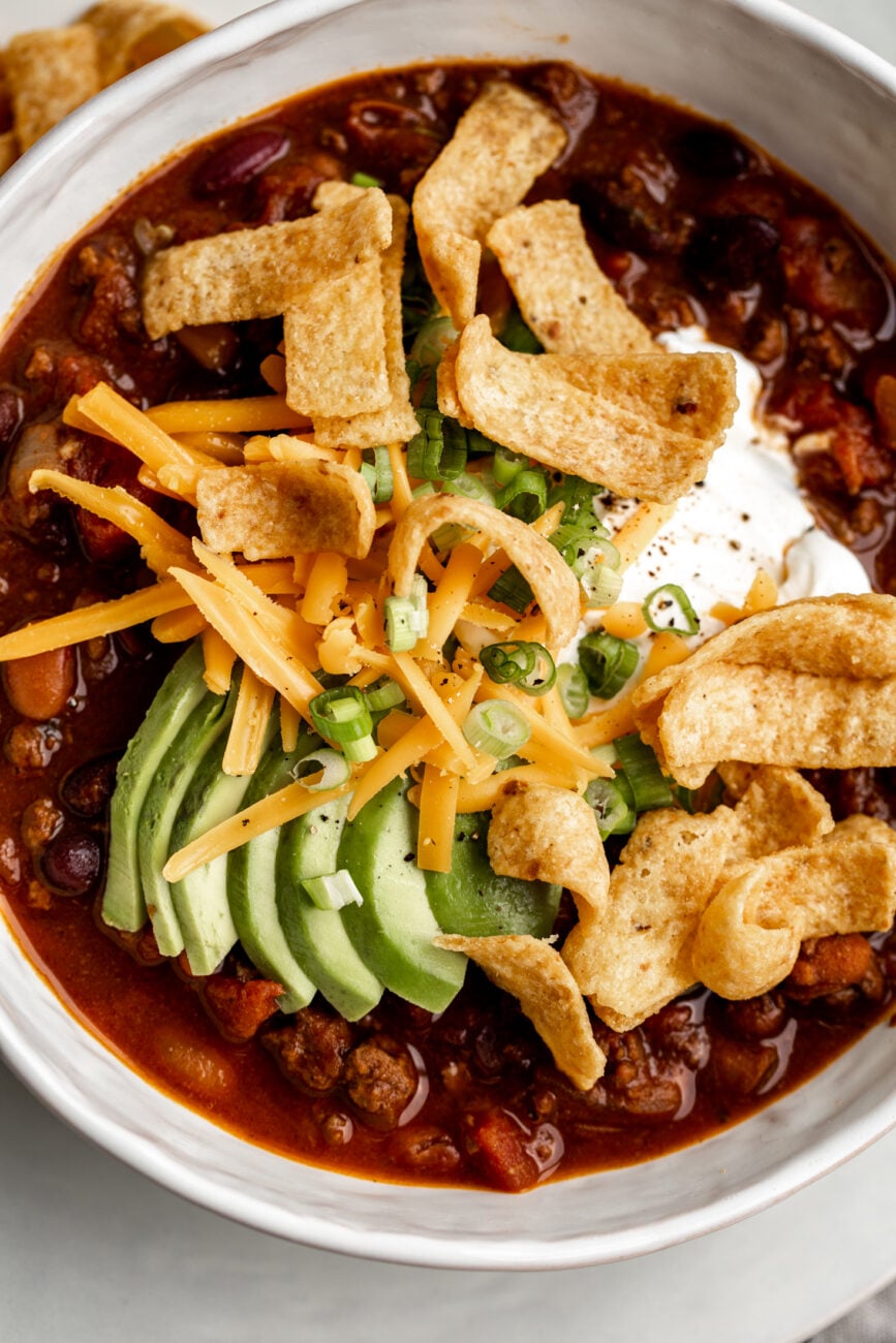 classic beef chili with corn chip fritos, avocado slices and Cheddar cheese.