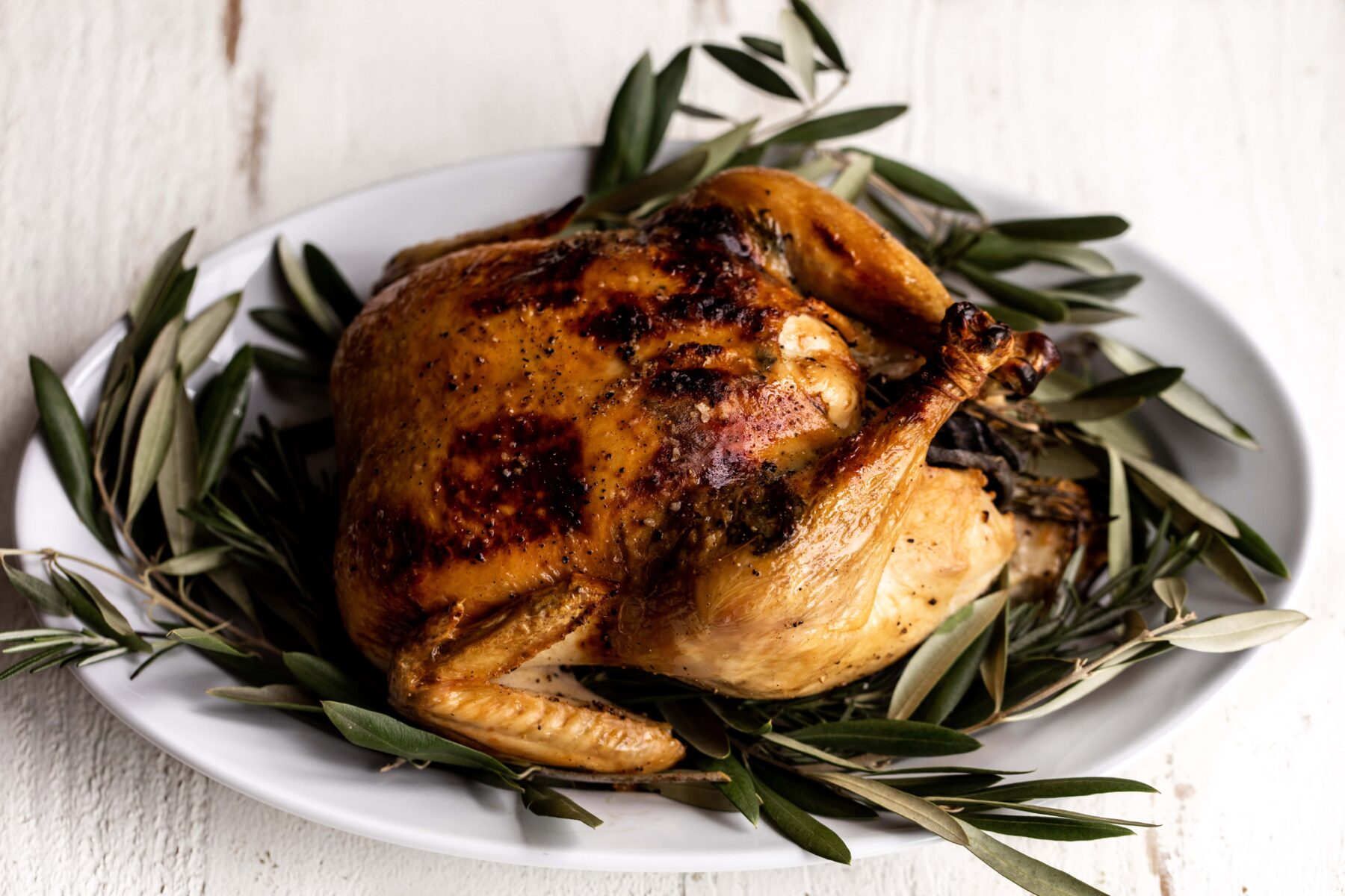 Dry brined whole herb roasted chicken on platter.