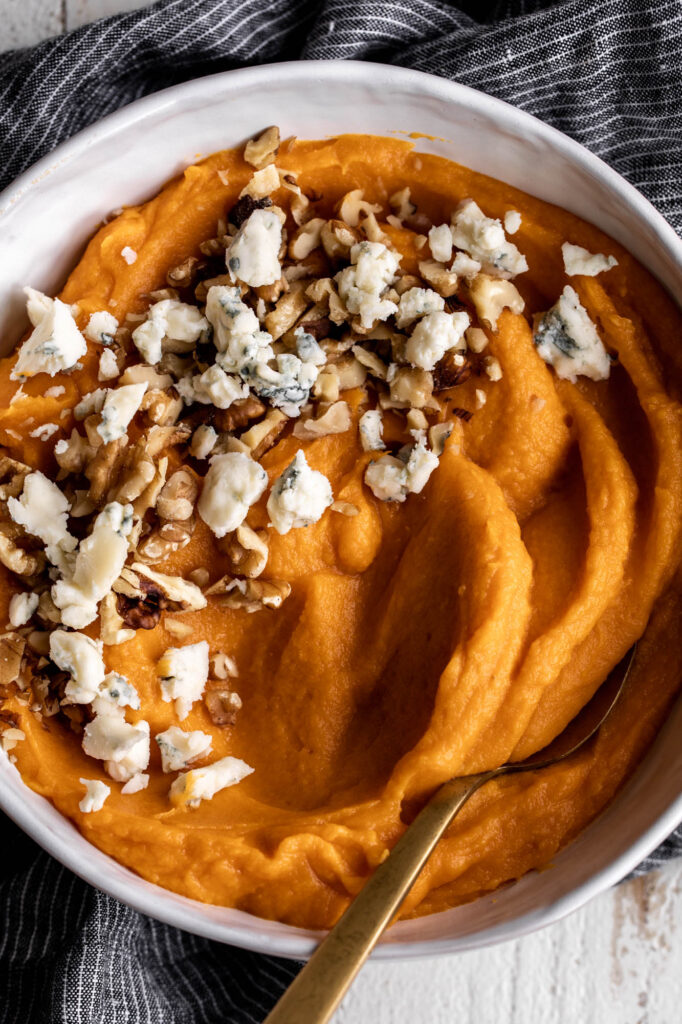 whipped sweet potatoes in white serving bowl with gorgonzola and walnuts thanksgiving side