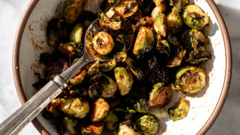 Balsamic Sriracha Roasted Brussels Sprouts in stone bowl with serving spoon