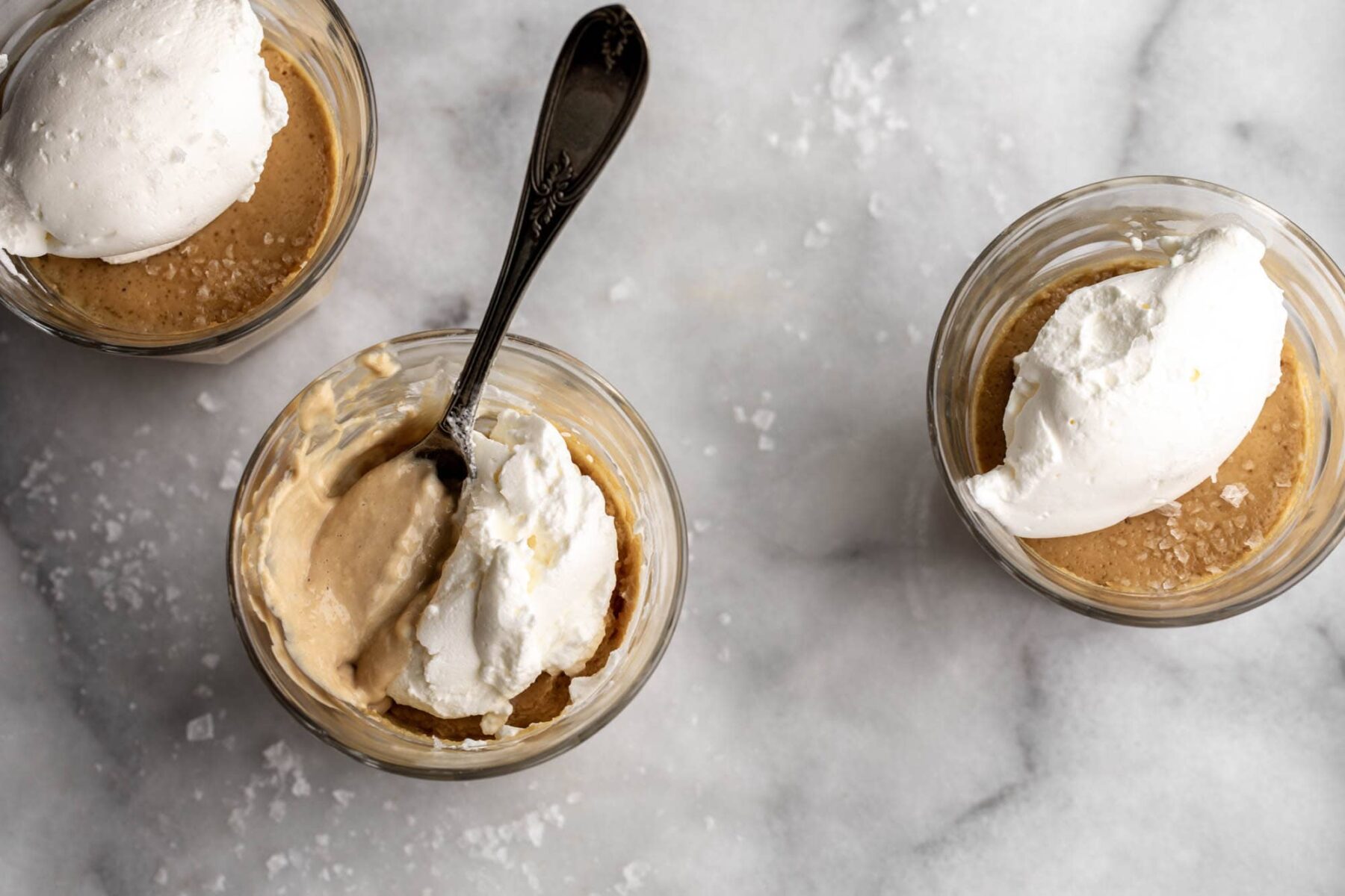 Salted Butterscotch Pots de Crème in small glass jars with whipped cream.