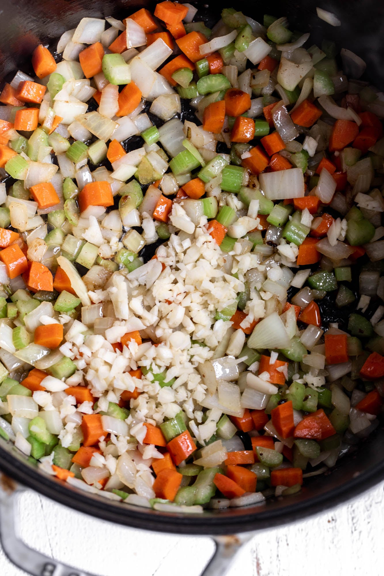 sautéed mirepoix celery carrots and onion with garlic in pot.