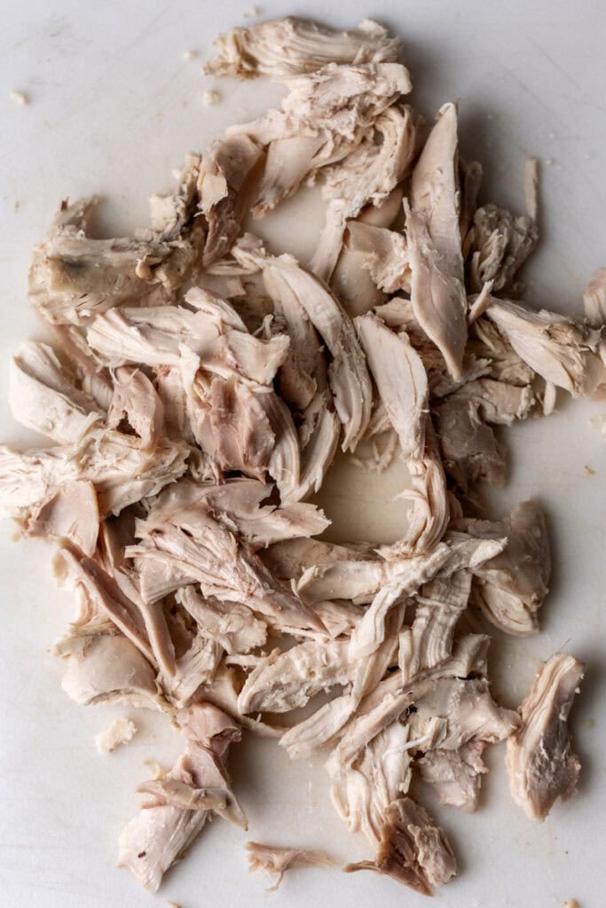 shredded chicken meat on cutting board.