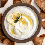 whipped feta dip with pita chips garnished with dried lemons and olive oil.