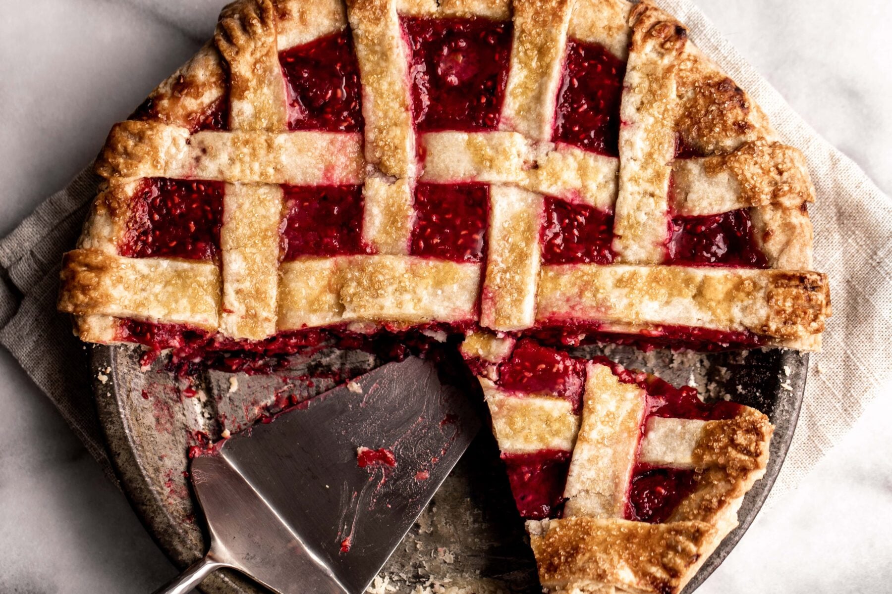 Raspberry pie with shortbread crust. Piece taken out with pie server.