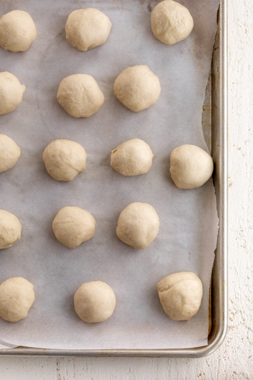 divided dough balls for bao buns on baking sheet.