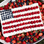 red white and blue flag cheesecake with berries and whipped cream.