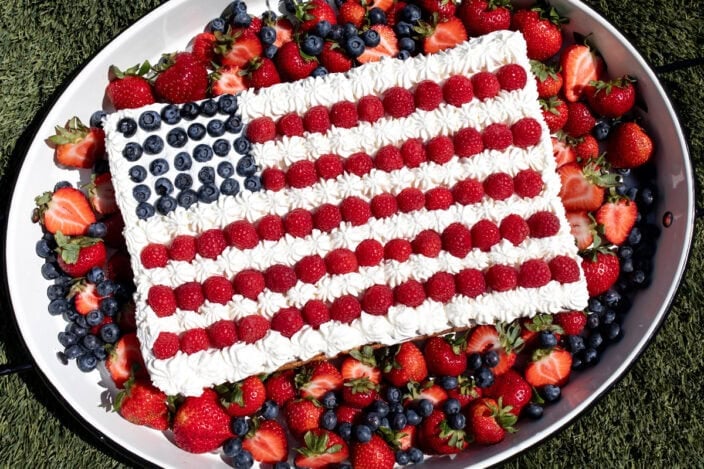 red white and blue flag cheesecake with berries and whipped cream.
