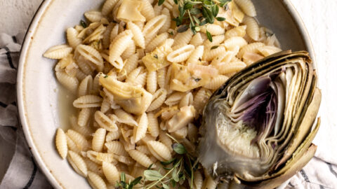 lemon artichoke pasta made with cavatelli with a half artichoke in the ceramic bowl topped with parmesan cheese