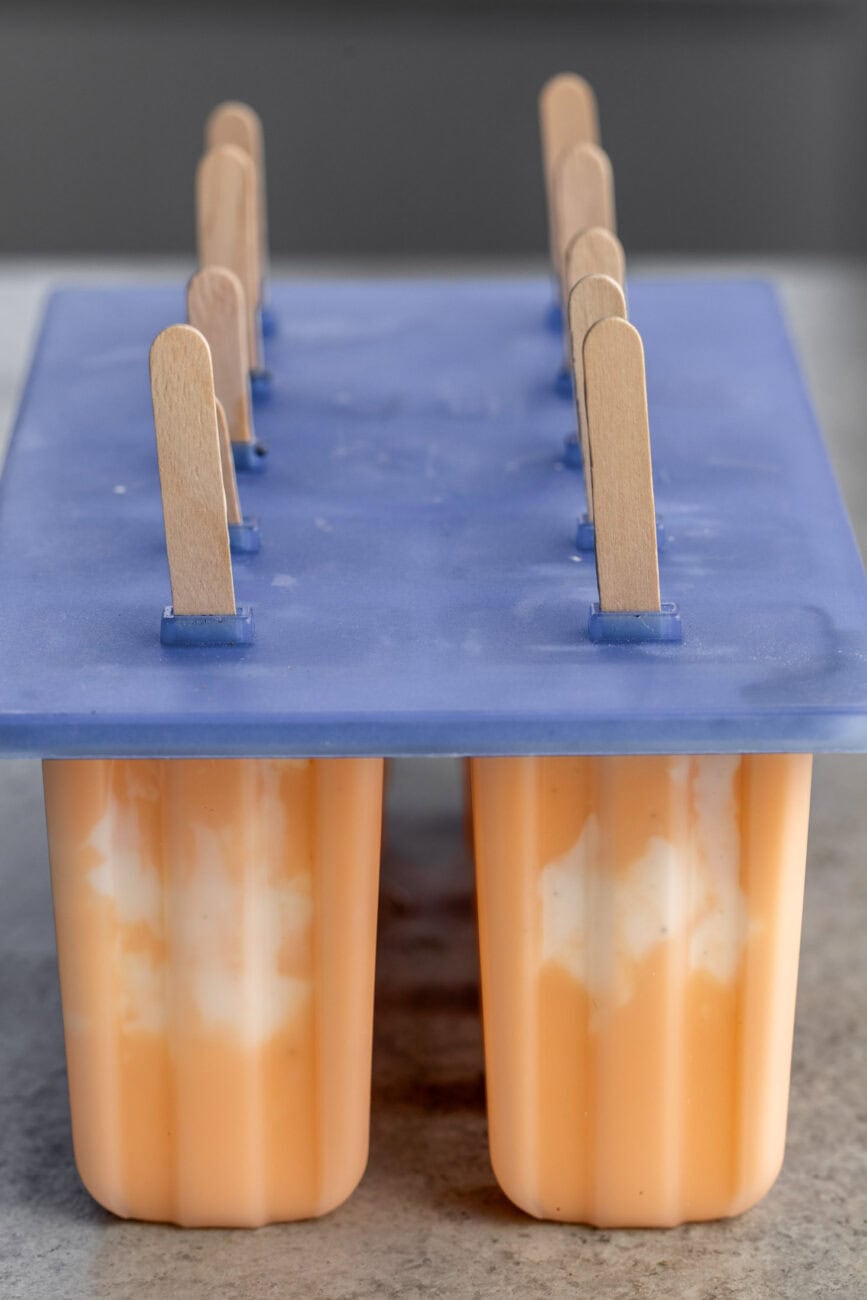 orange creamsicle ice pops in mold with popsicle stick.