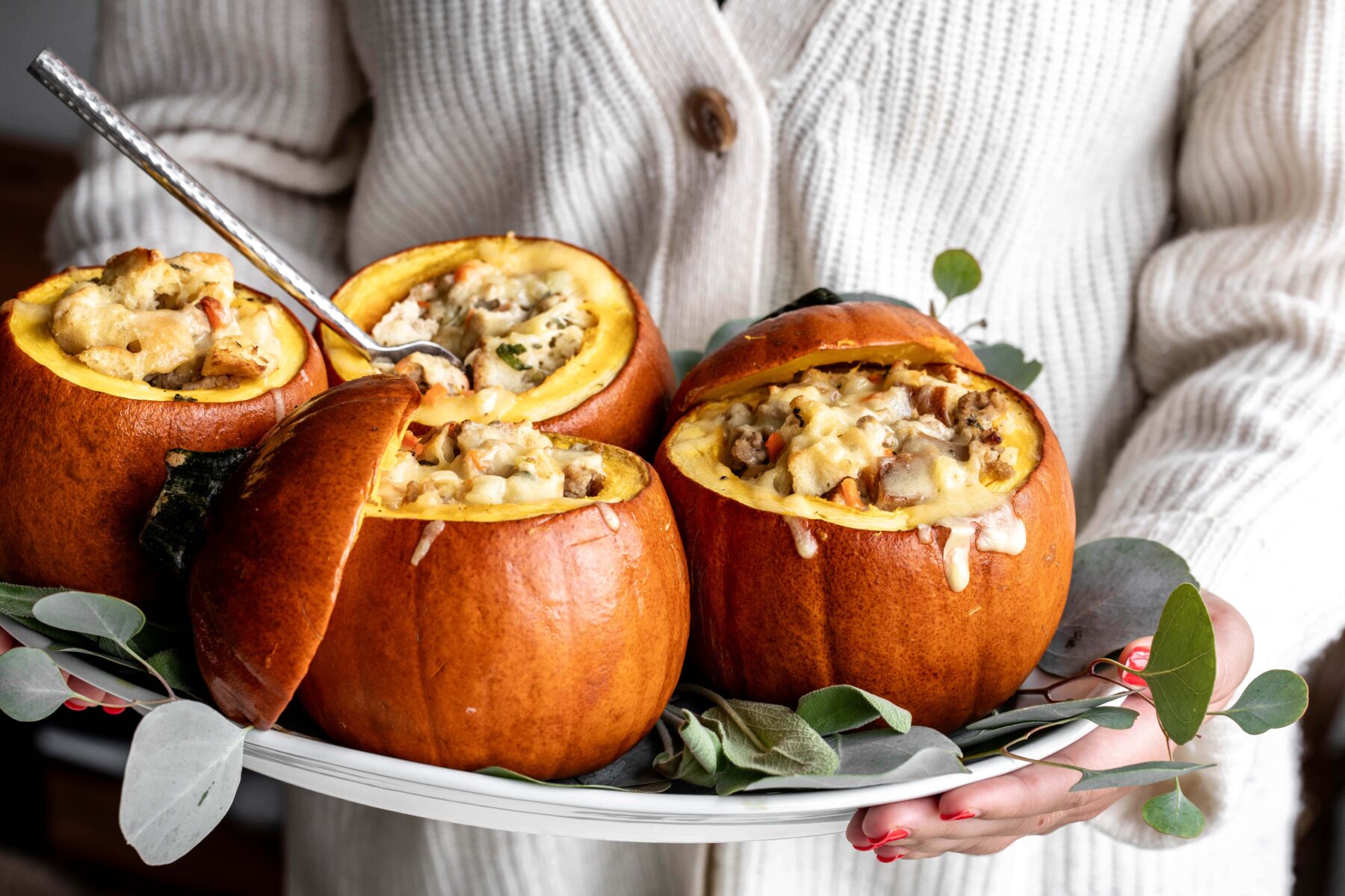 Ground Turkey and Brown Butter Stuffed Pumpkins on white platter garnished with sage and eucalyptus.