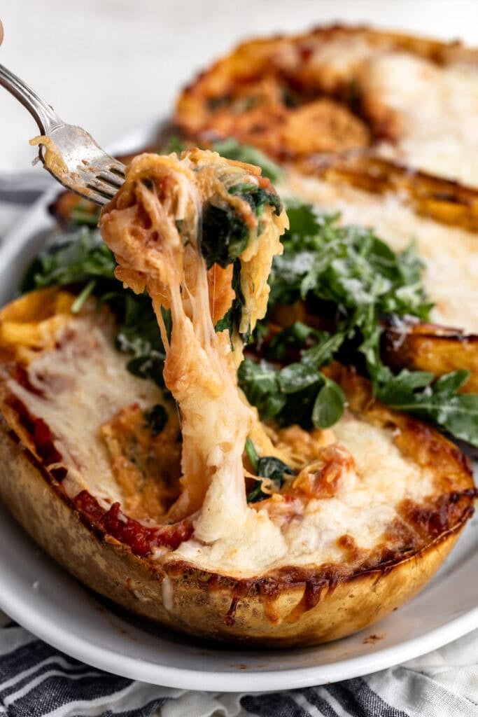 spaghetti squash lasagna boats with fork pulling mixture.