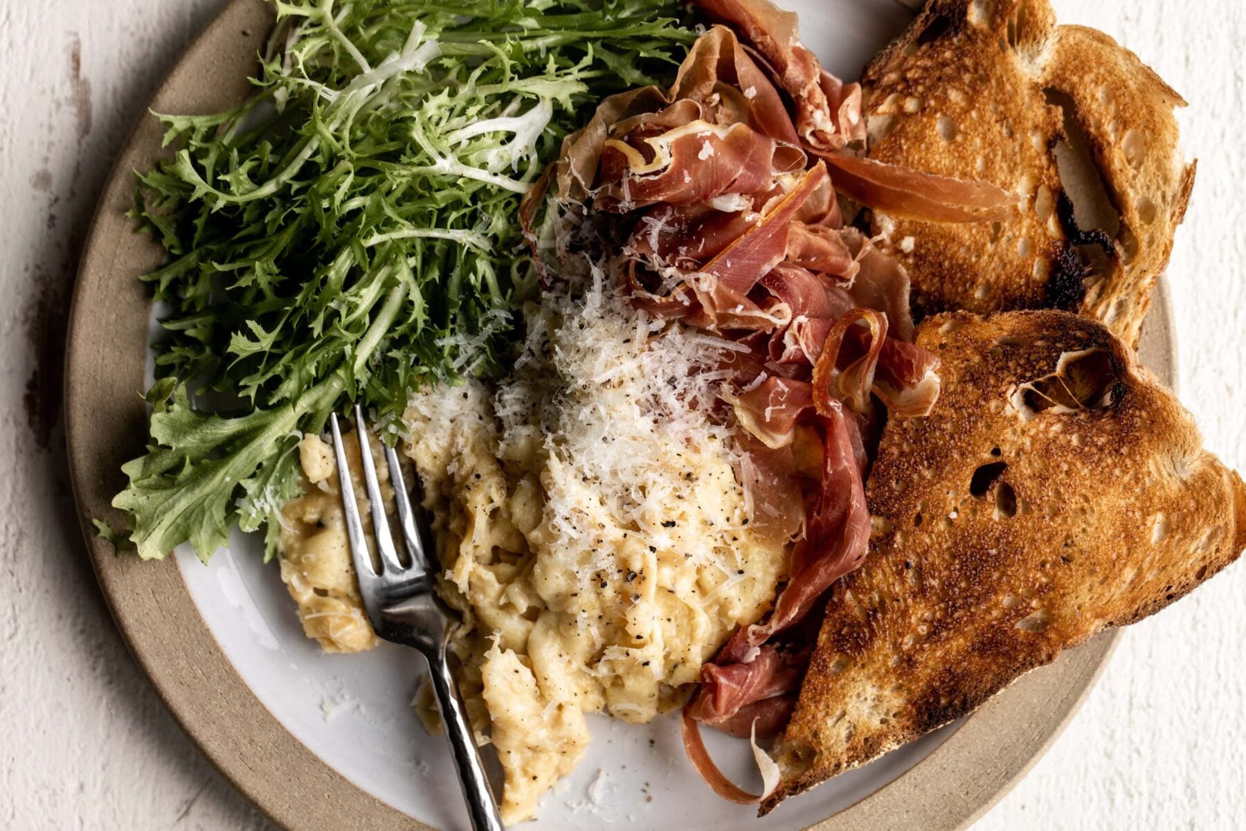 cacio e pepe cheesy eggs topped with pecorino romano cheese and cracked pepper.