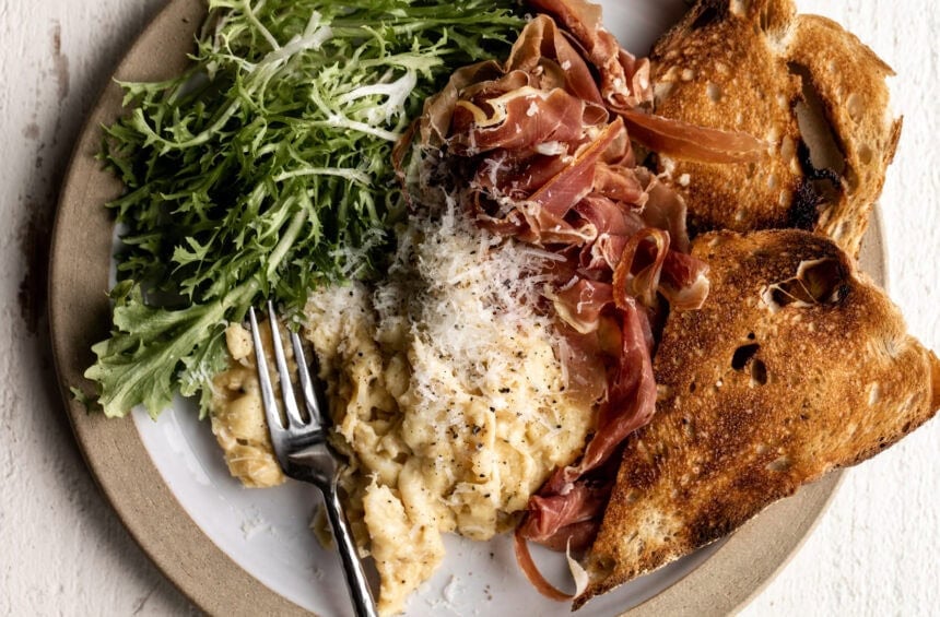 cacio e pepe cheesy eggs topped with pecorino romano cheese and cracked pepper.