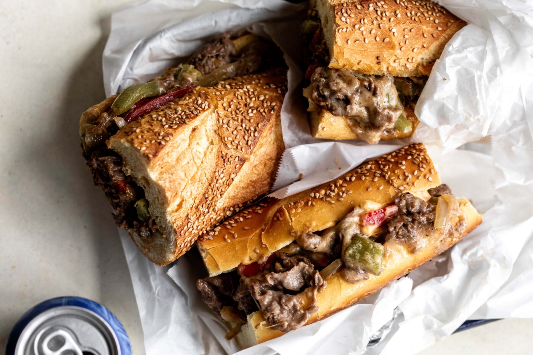 Philly cheesesteak sandwich with ribeye steak onions and peppers with cheese on sesame hoagie roll.