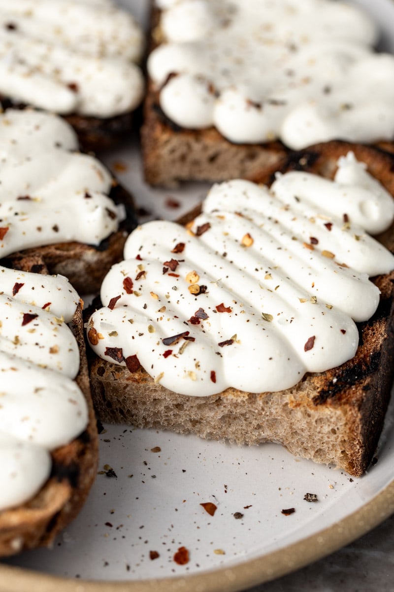 whipped ricotta toasts with ricotta piped on bread with red pepper flakes.