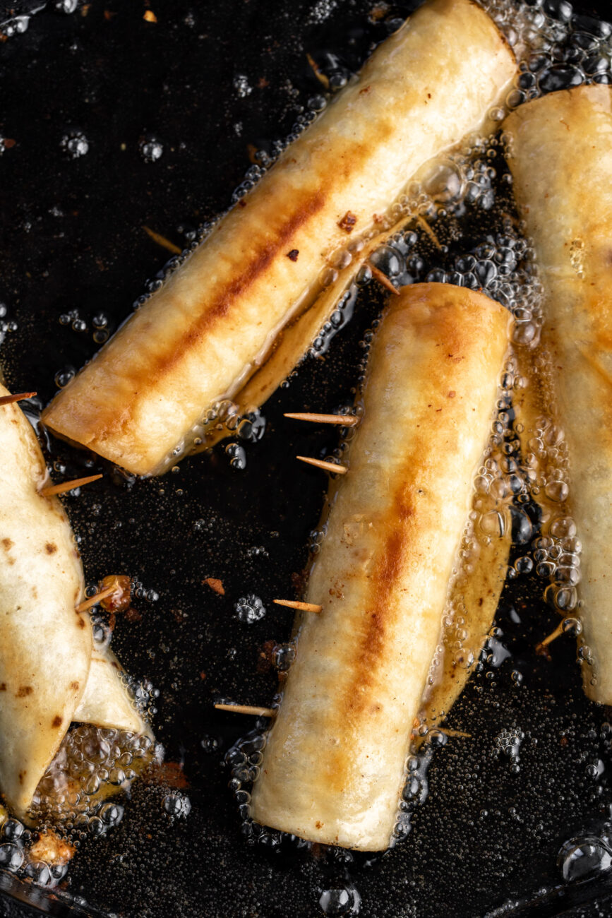fried chicken flautas in oil.