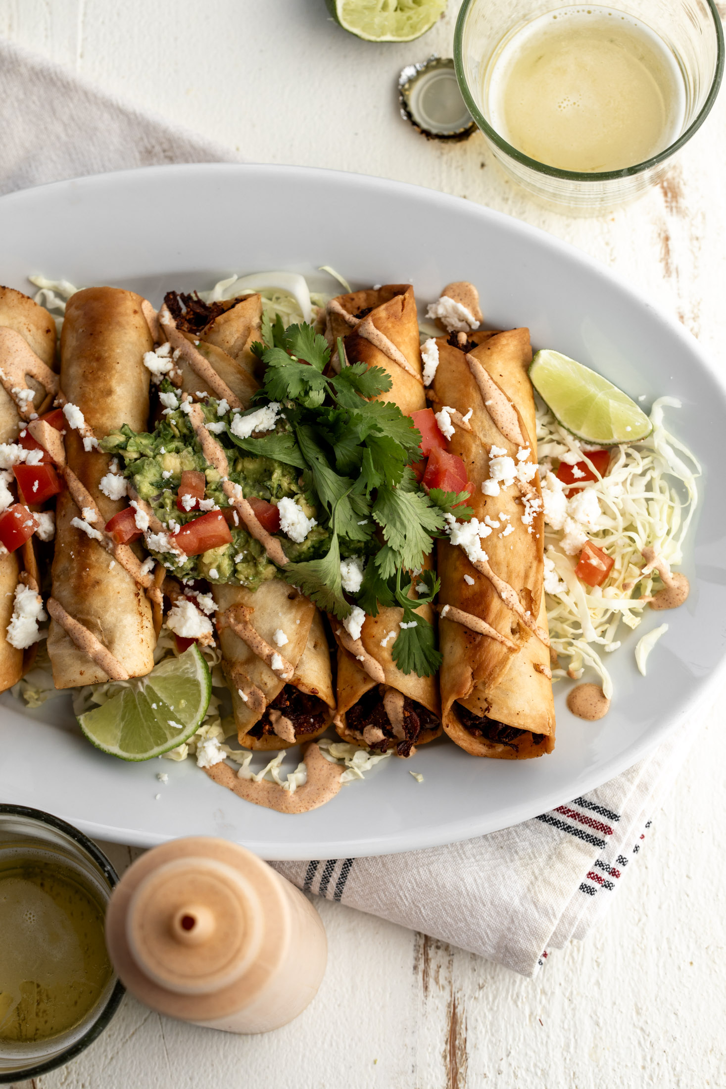 chicken flautas with mushroom and roasted corn with chipotle mayonnaise topped with guacamole diced tomatoes and cilantro.
