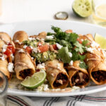 chicken flautas with mushroom and roasted corn with chipotle mayonnaise topped with guacamole diced tomatoes and cilantro.