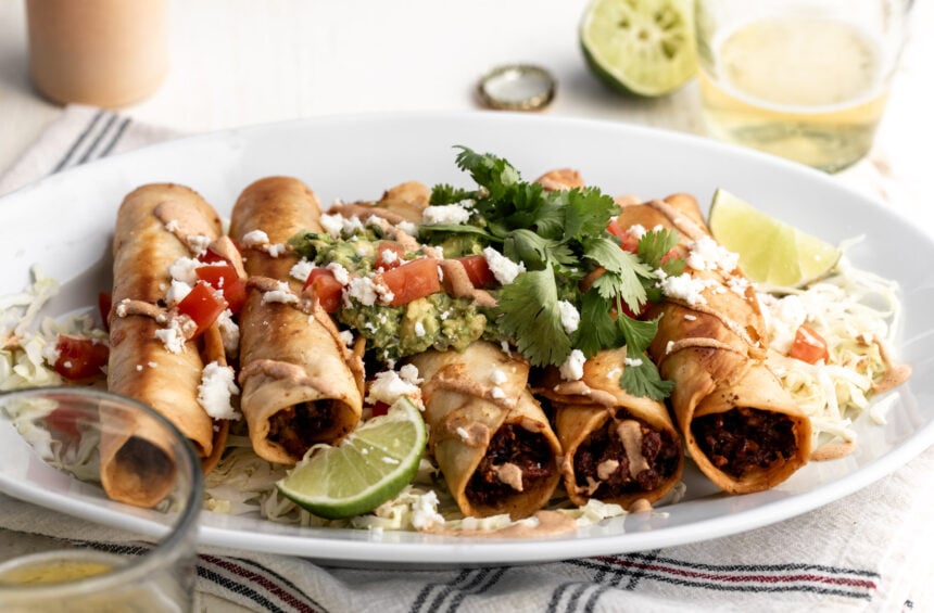 chicken flautas with mushroom and roasted corn with chipotle mayonnaise topped with guacamole diced tomatoes and cilantro.