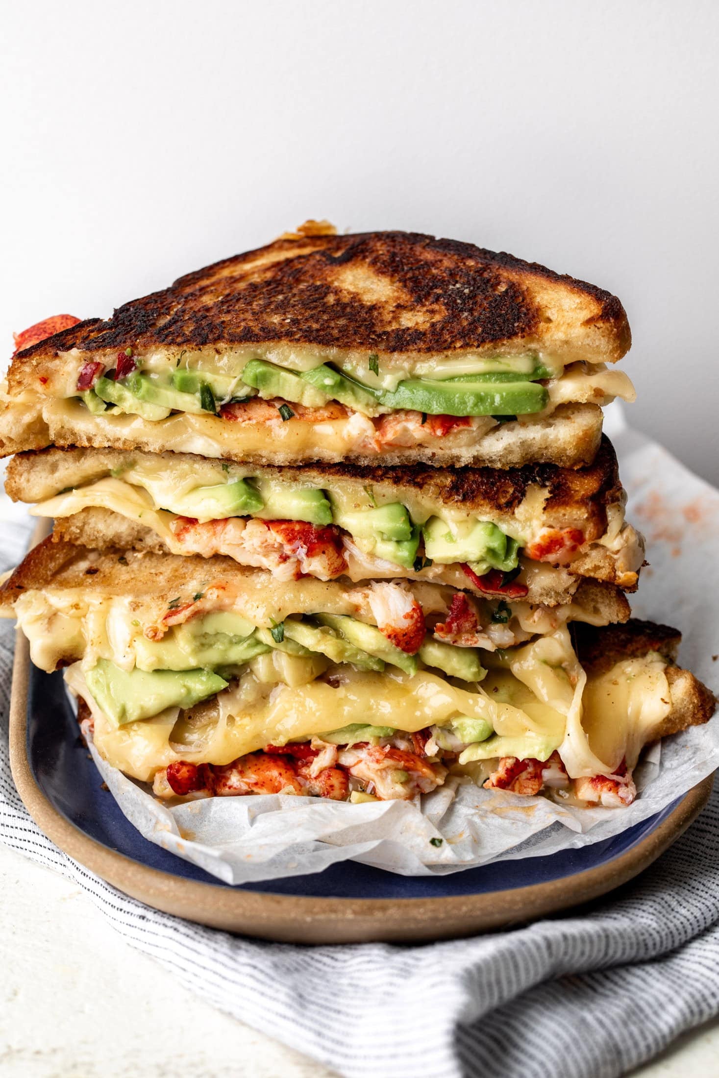 lobster grilled cheese with avocado stacked on plate