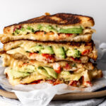 lobster avocado grilled cheese stacked on plate.